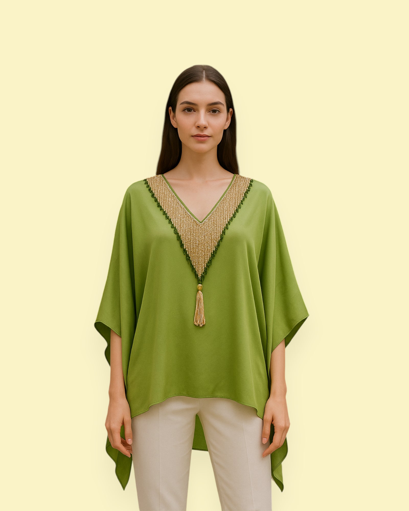 Woman wearing a green kaftan with beaded neckline on a light yellow background