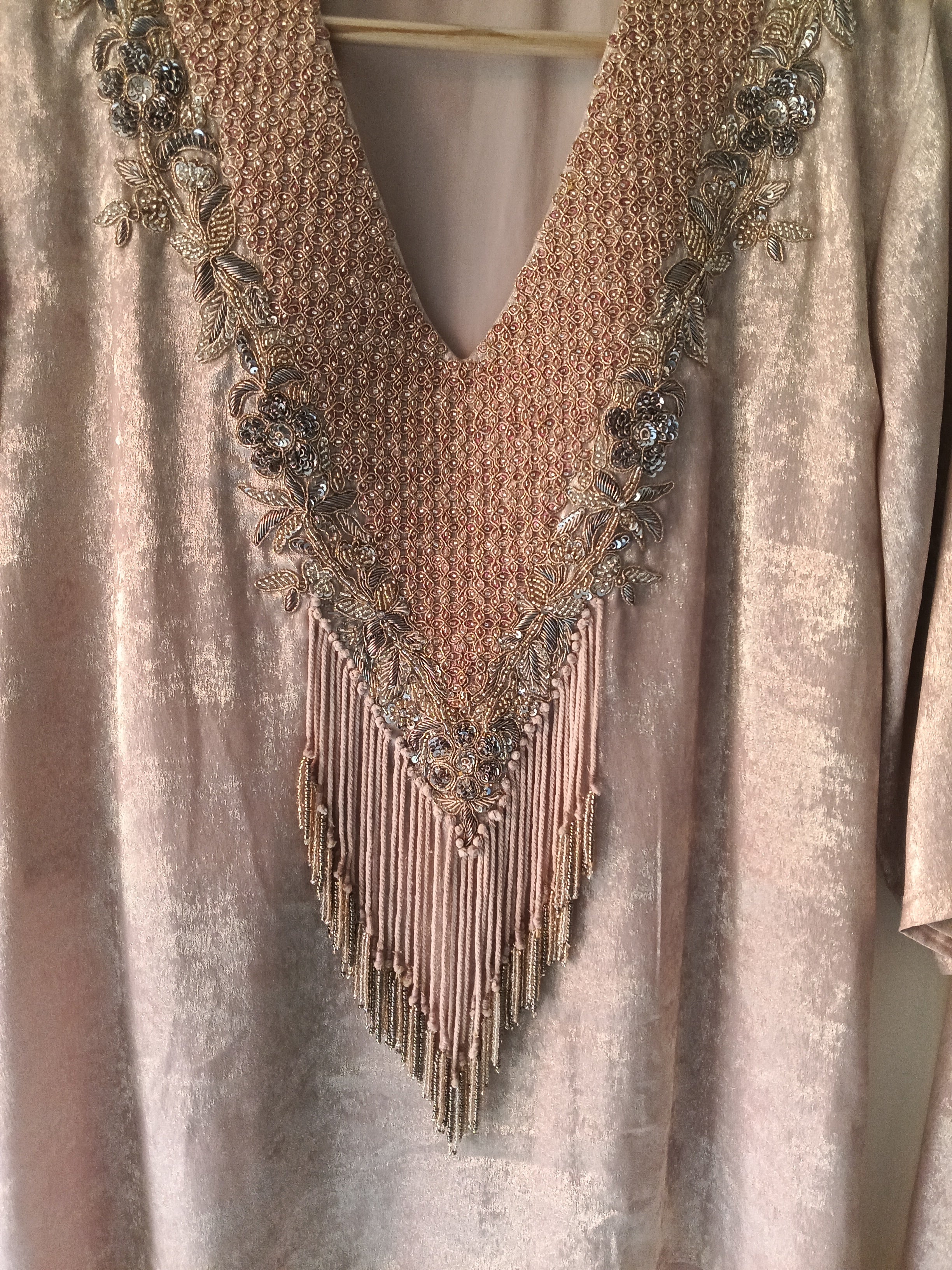 Close-up of a decorative necklace with fringe on a textured fabric background