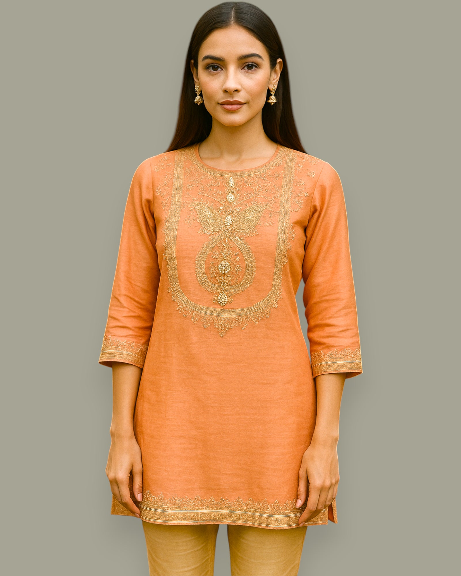 Woman wearing an orange embroidered kurta against a gray background