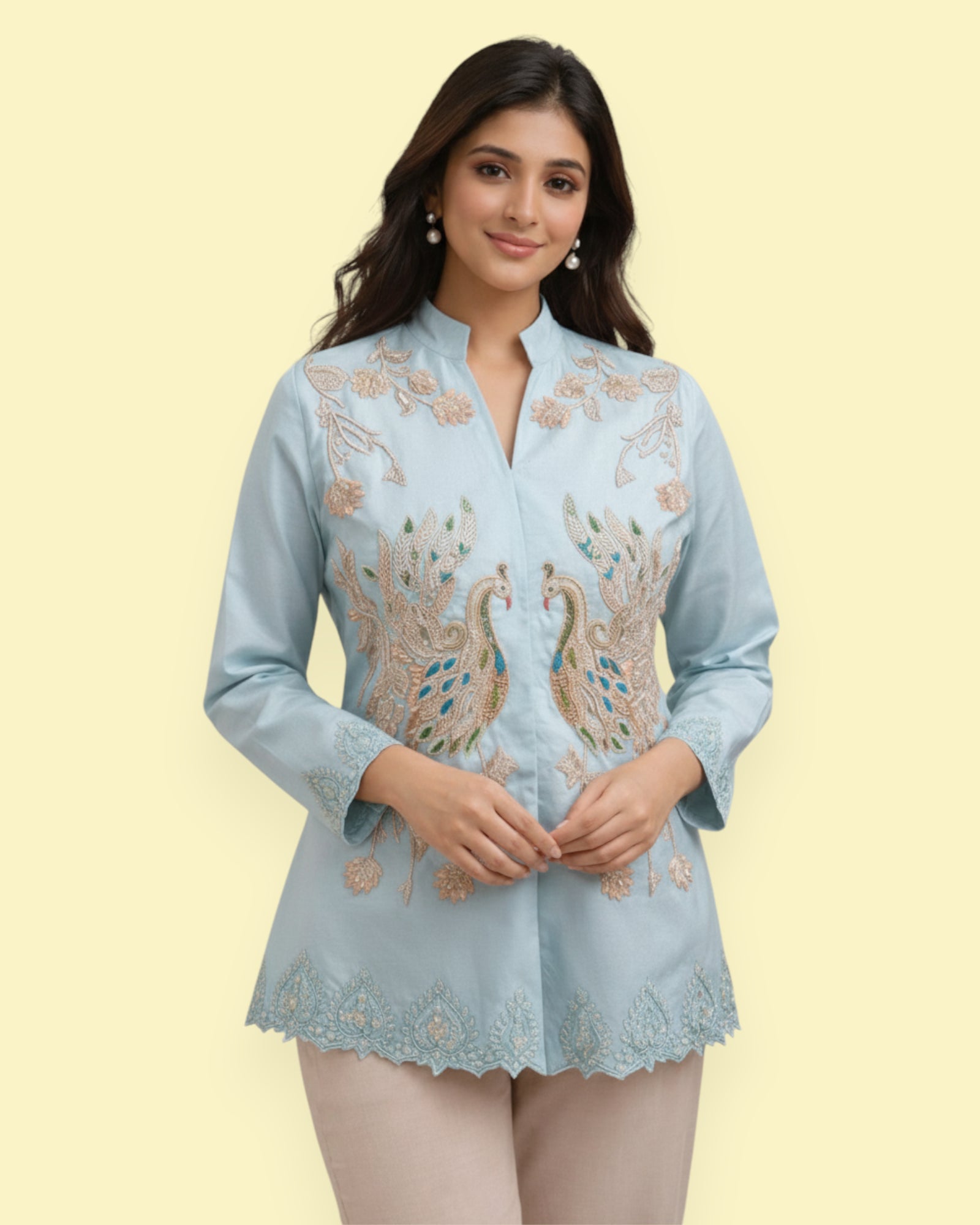 Woman wearing a light blue embroidered Jacket with peacock designs on a beige background