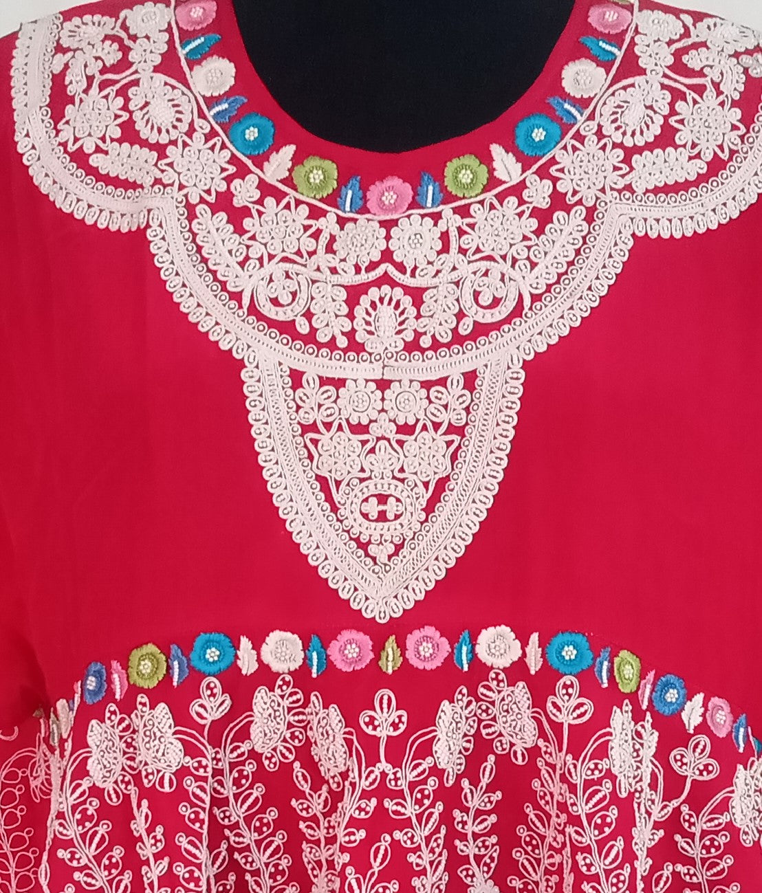Red garment with white floral embroidery on a plain background