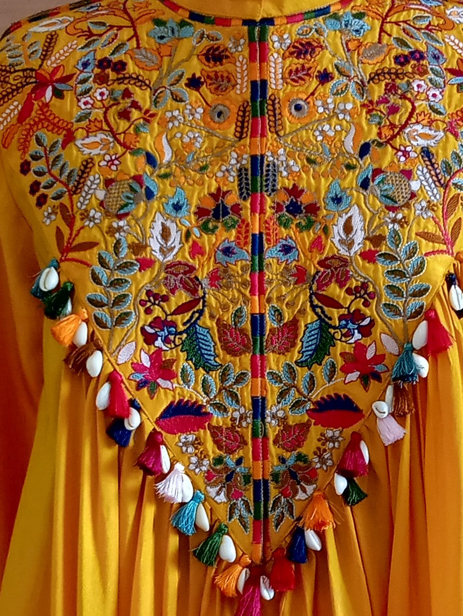 Yellow garment with intricate floral embroidery and colorful tassels