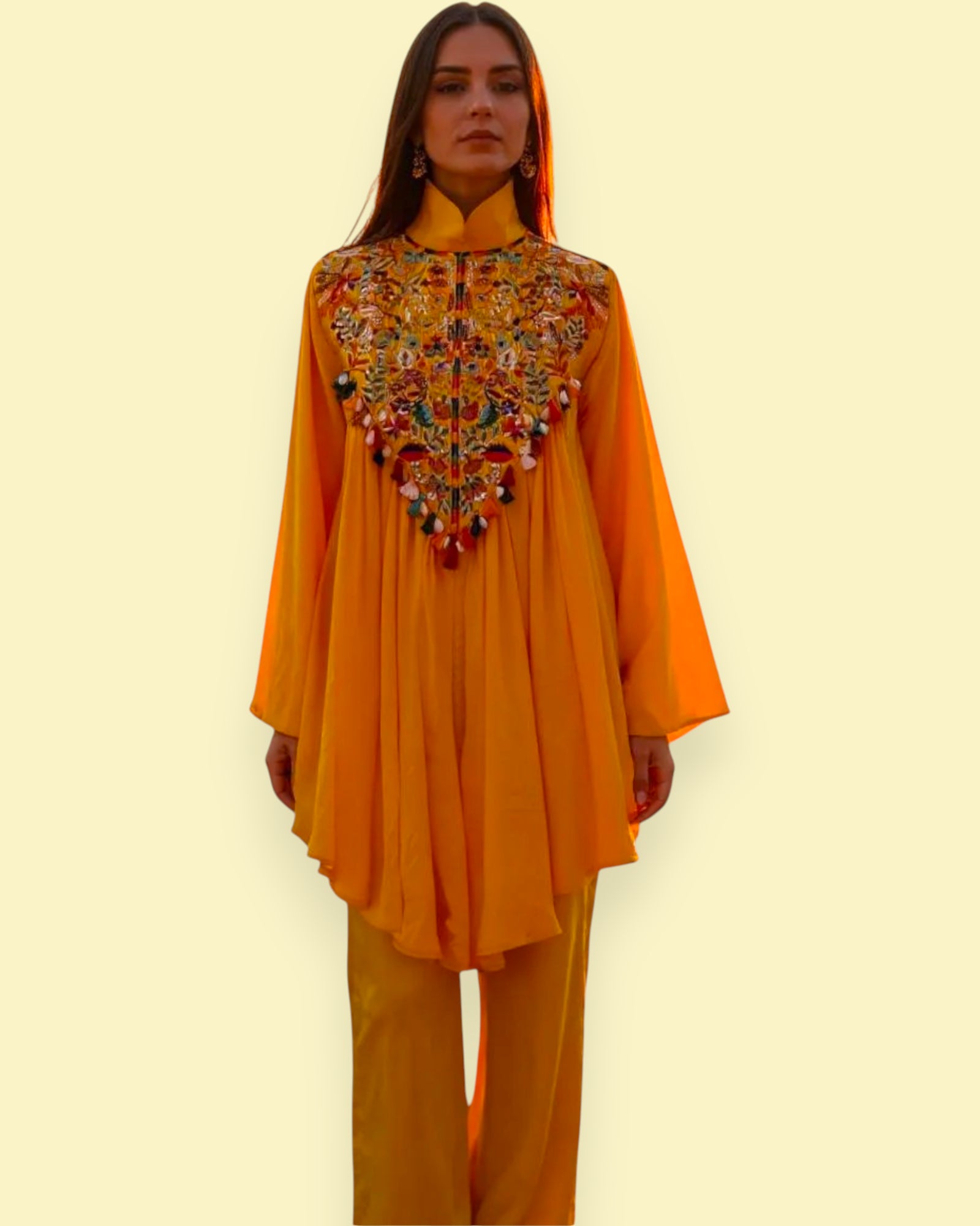 Woman wearing a mustard yellow embroidered top and pants on a light beige background