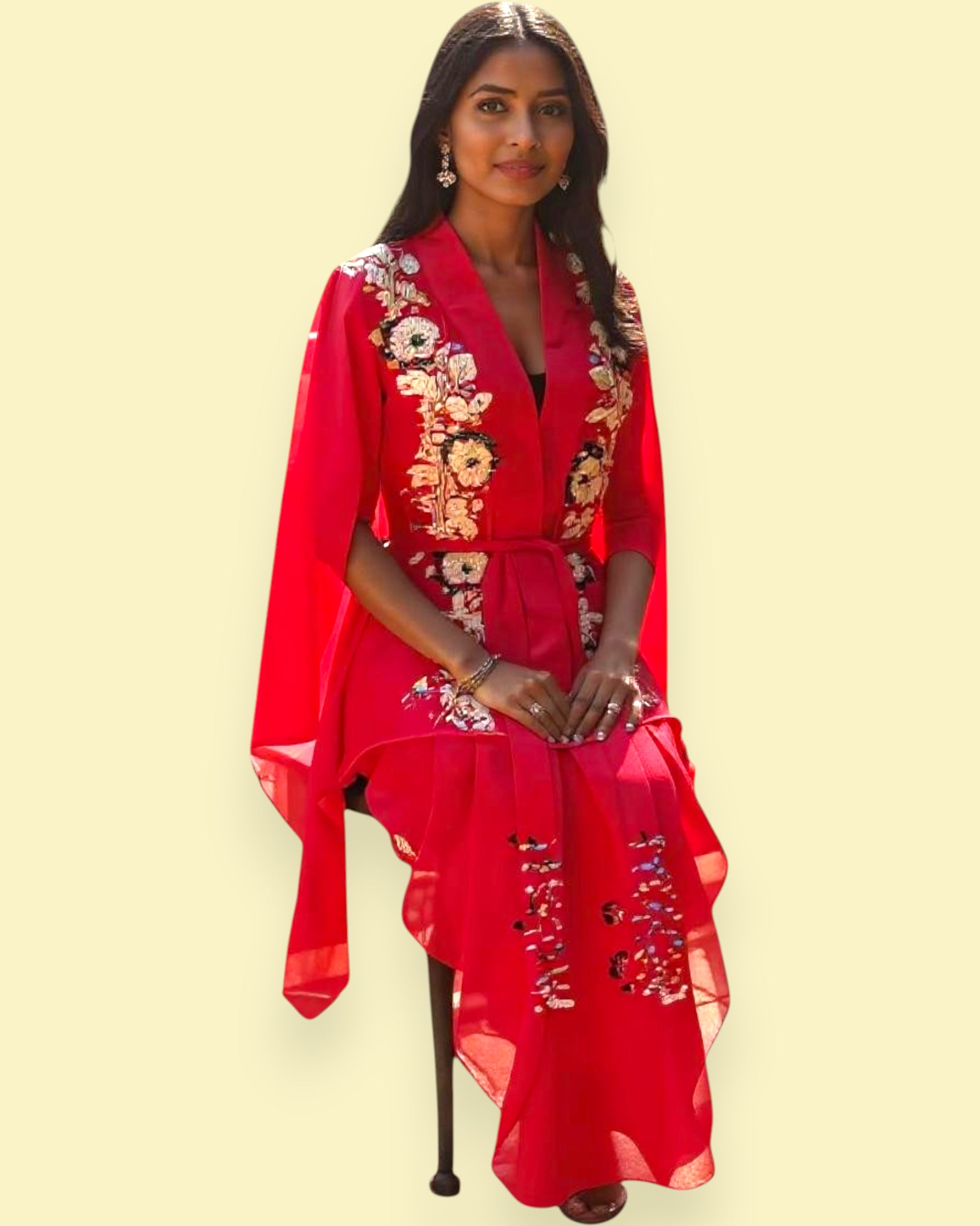 Woman wearing a red dress with floral embroidery on a beige background