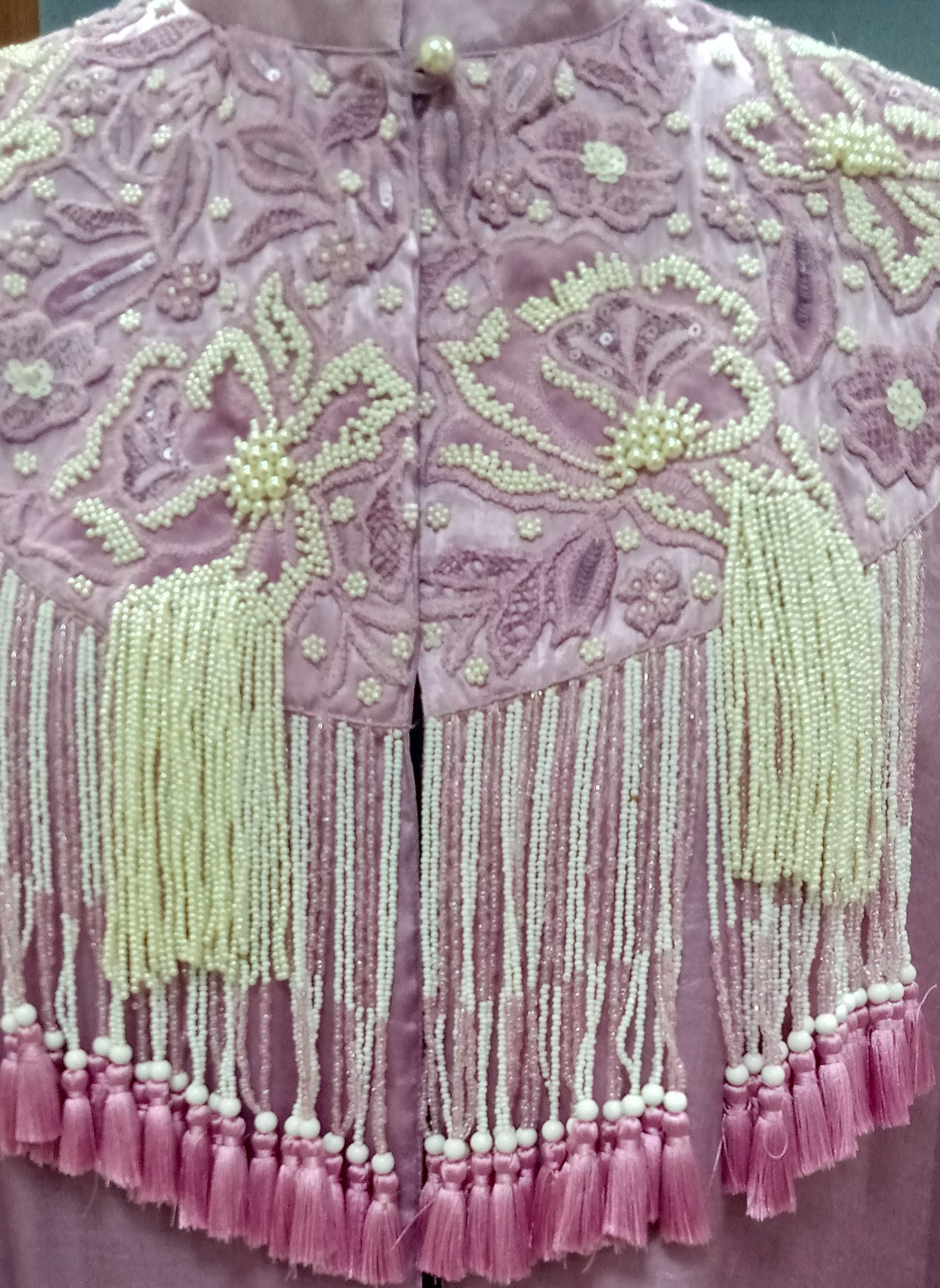 Pink embroidered garment with tassels and beads