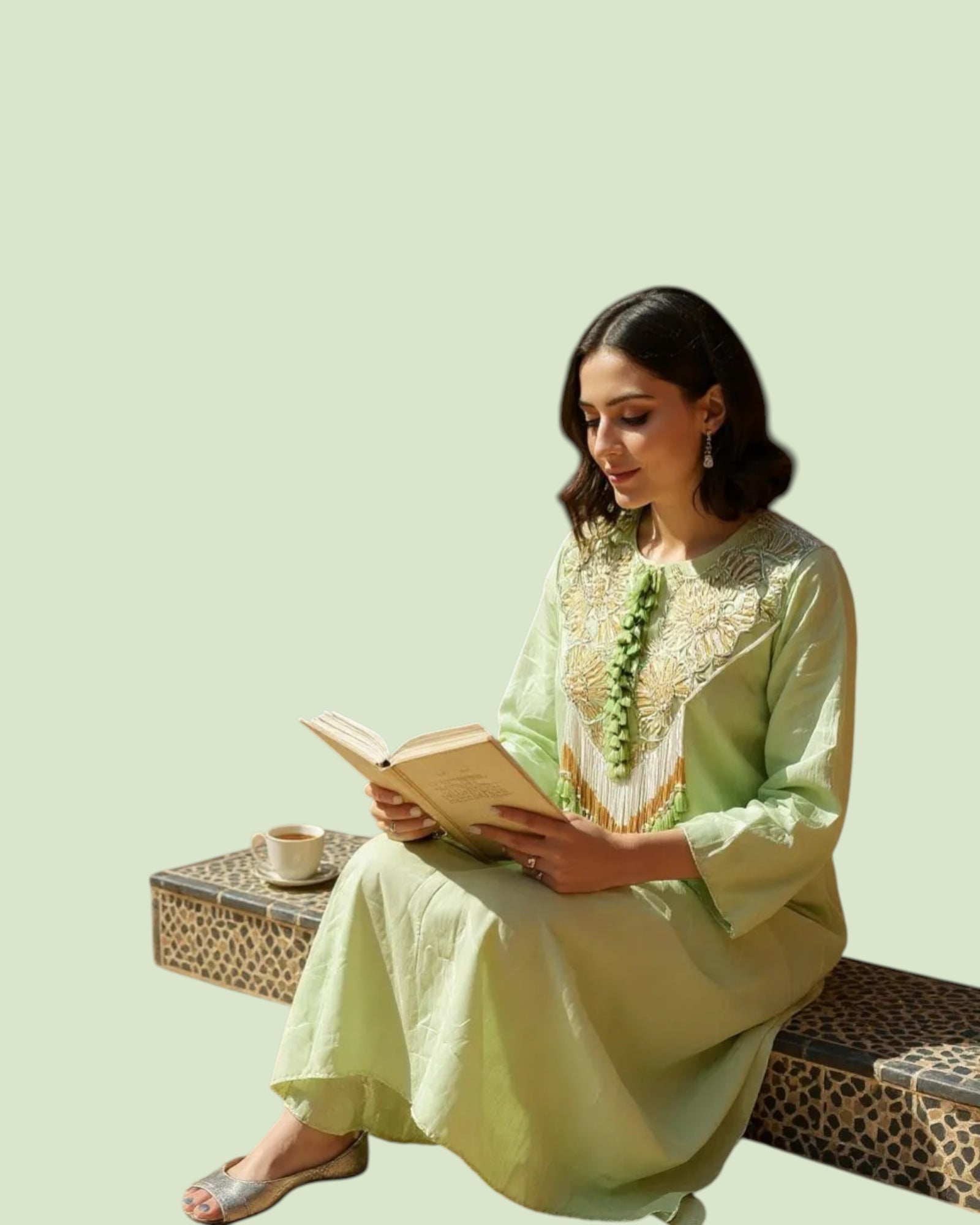 Woman in a light green traditional outfit reading a book on a light green background