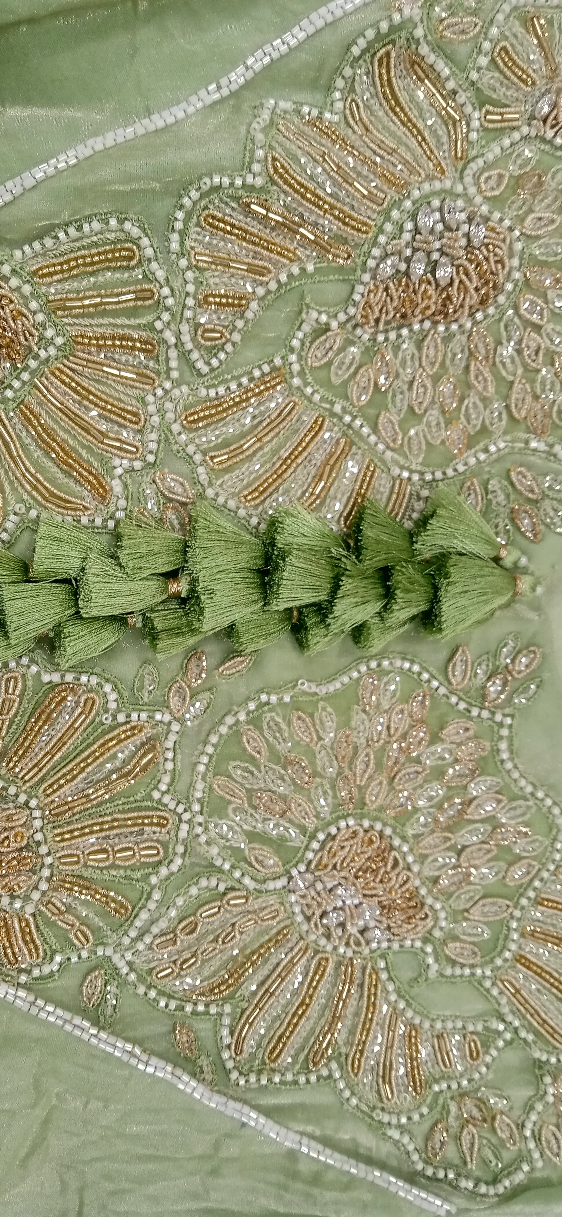 Close-up of green fabric with intricate gold and silver embroidery