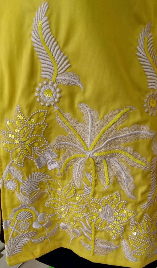 Yellow fabric with intricate white floral embroidery