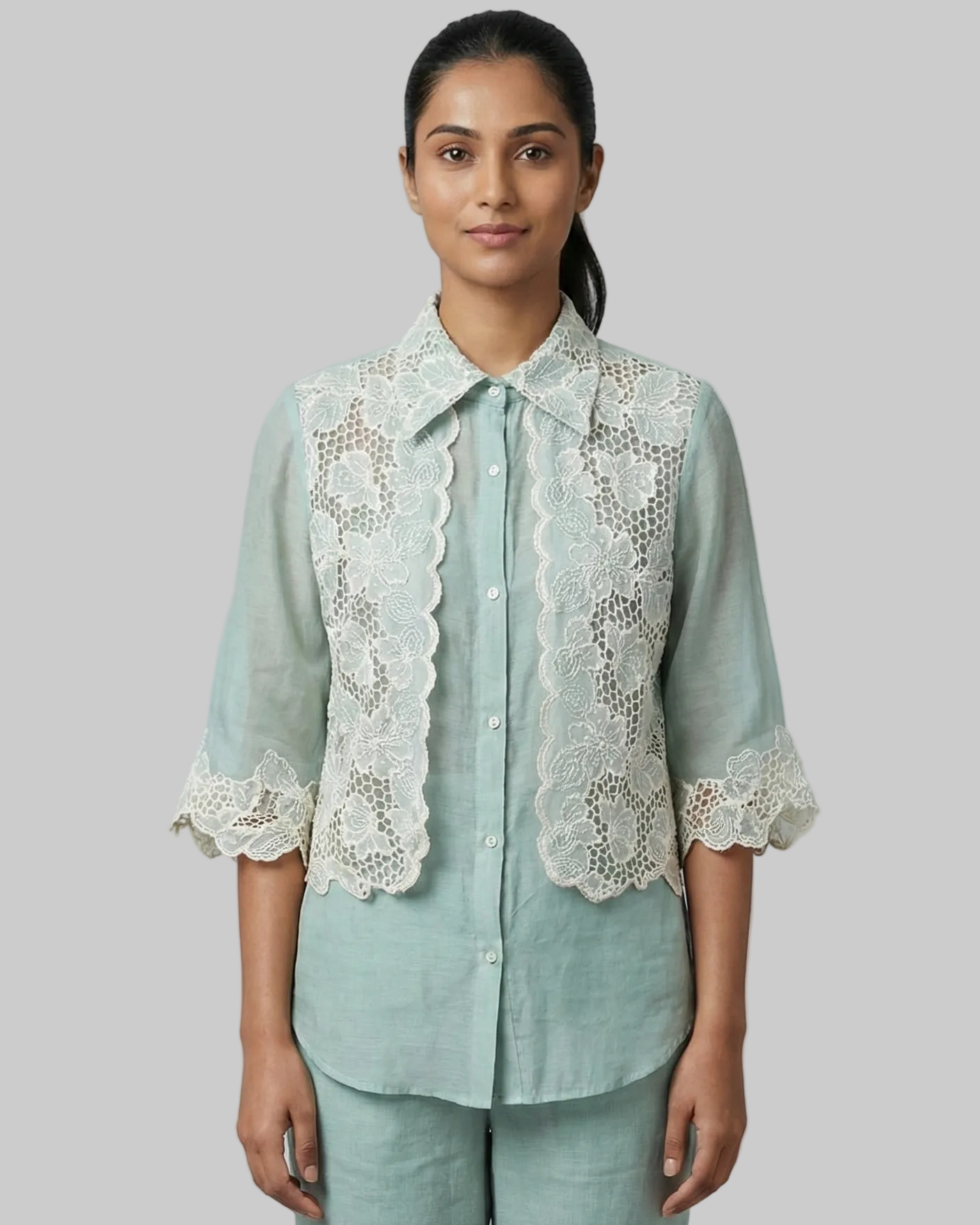 Woman wearing a light blue shirt with lace details on a gray background
