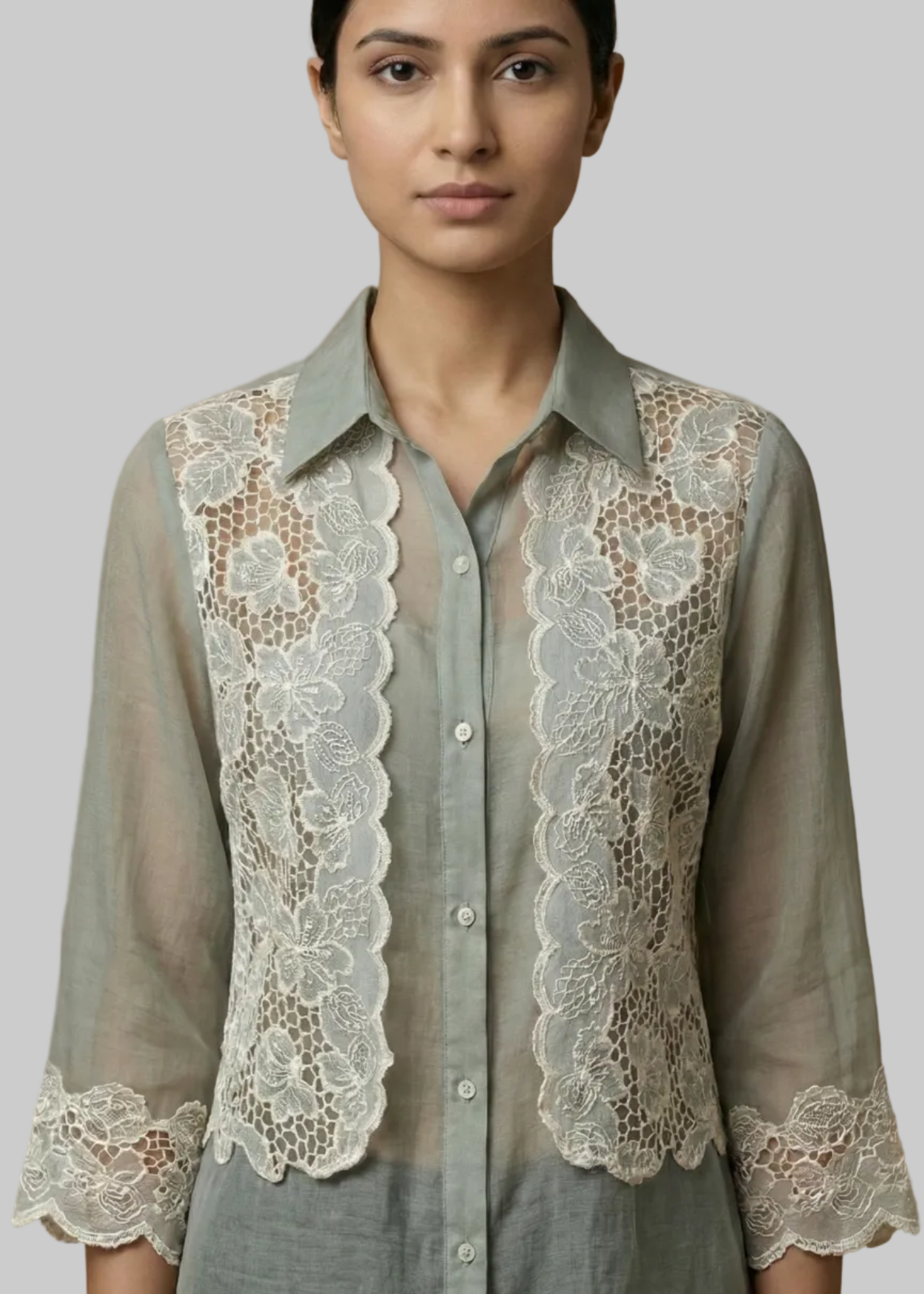 Woman wearing a light Blue shirt with lace detailing on a plain background