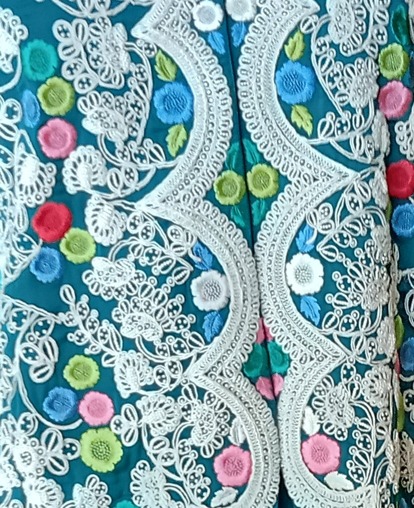 Close-up of intricate lace fabric with colorful floral patterns on a blue background