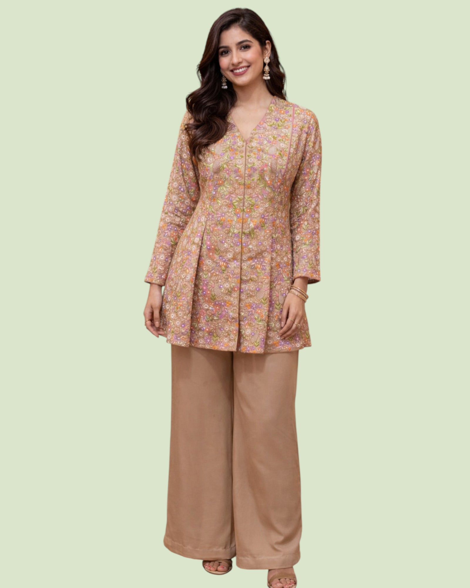 Woman wearing a floral top and brown pants on a light green background