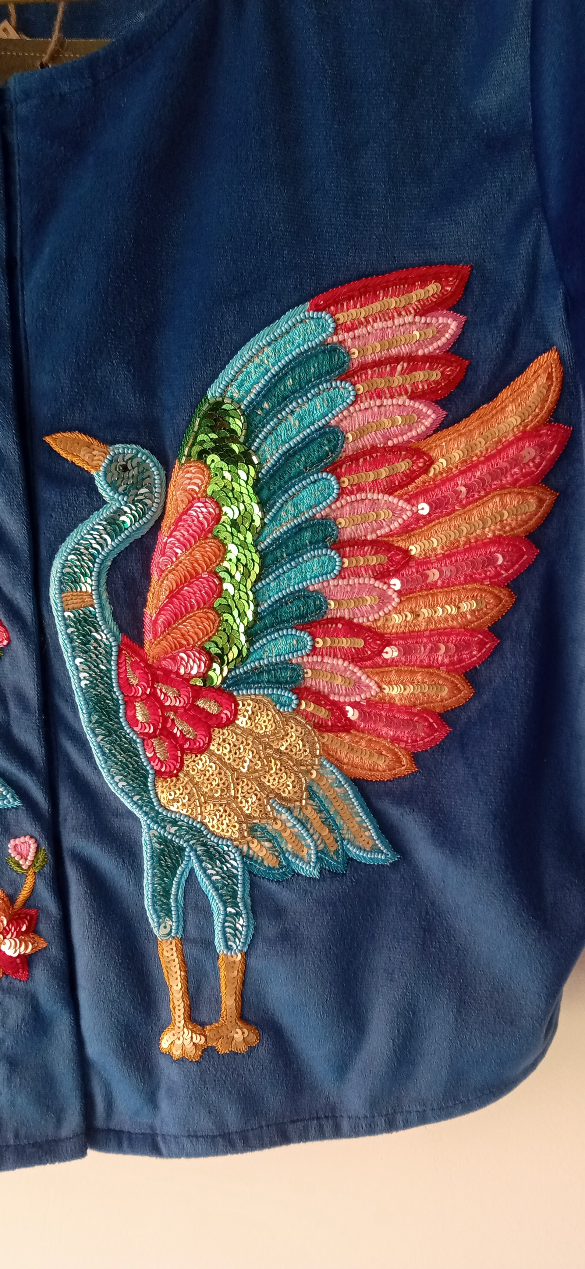 Colorful embroidered bird design on a dark blue fabric background