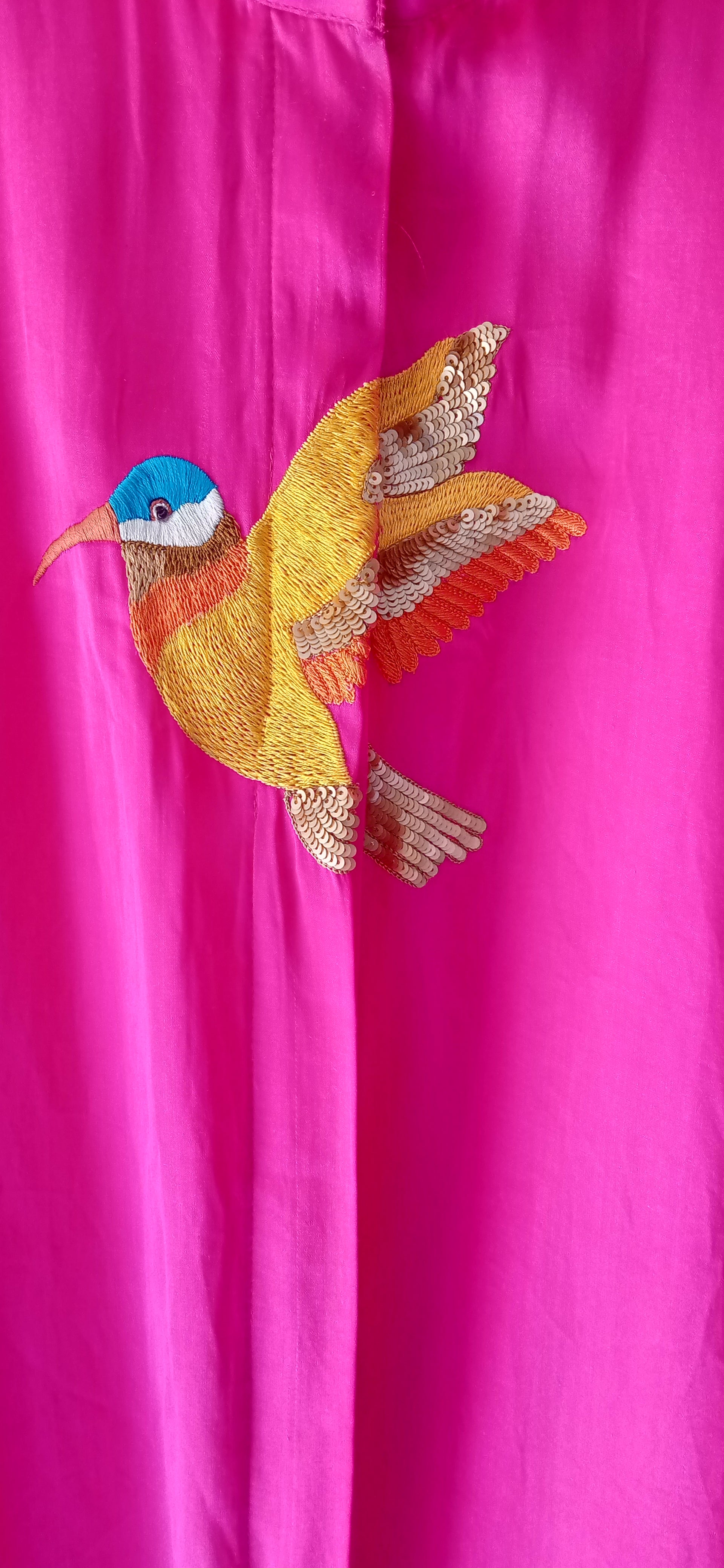 Embroidered bird design on a pink fabric background