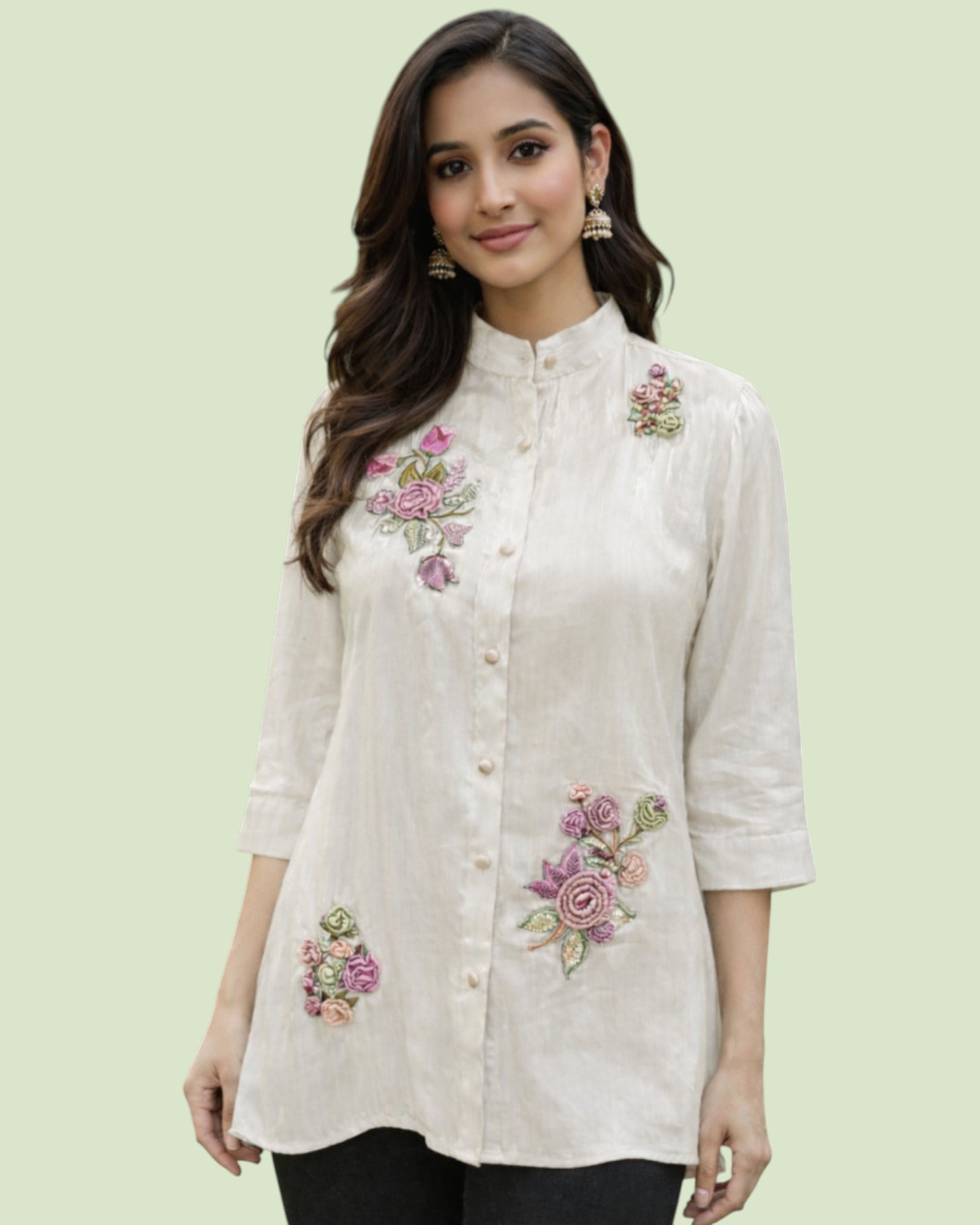 Woman wearing a white embroidered shirt with floral designs on a light green background
