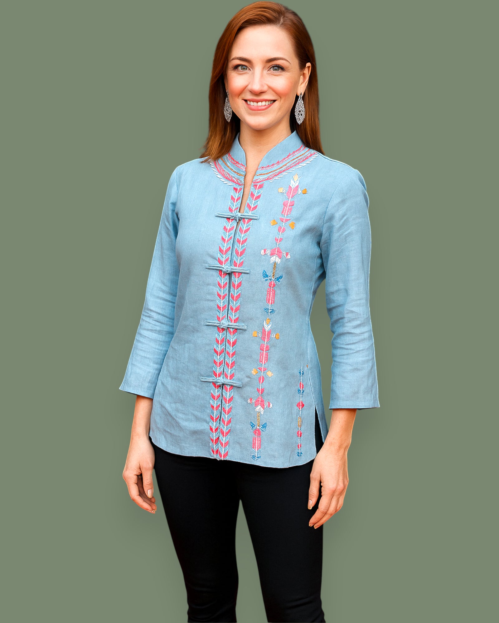 Woman wearing a light blue embroidered Shirt against a gray background