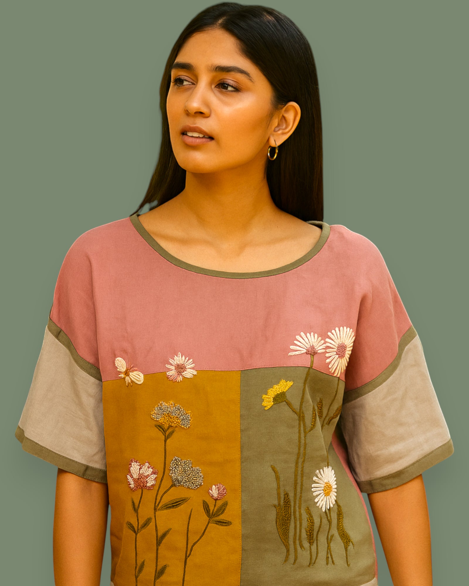 Woman wearing a pink and brown top with floral patterns on a plain background