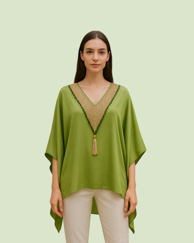 Woman wearing a green kaftan with a beaded neckline on a light green background