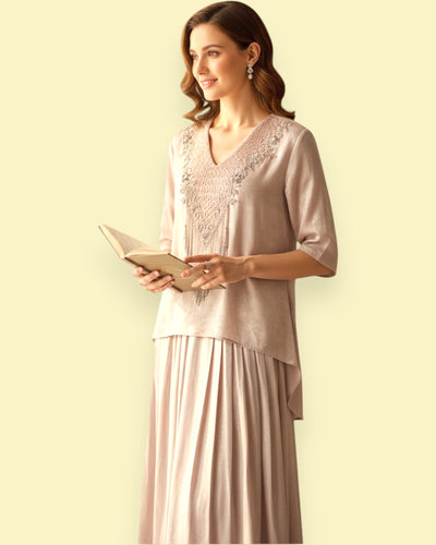 Woman in a dress with Embroidery holding a book against a plain background