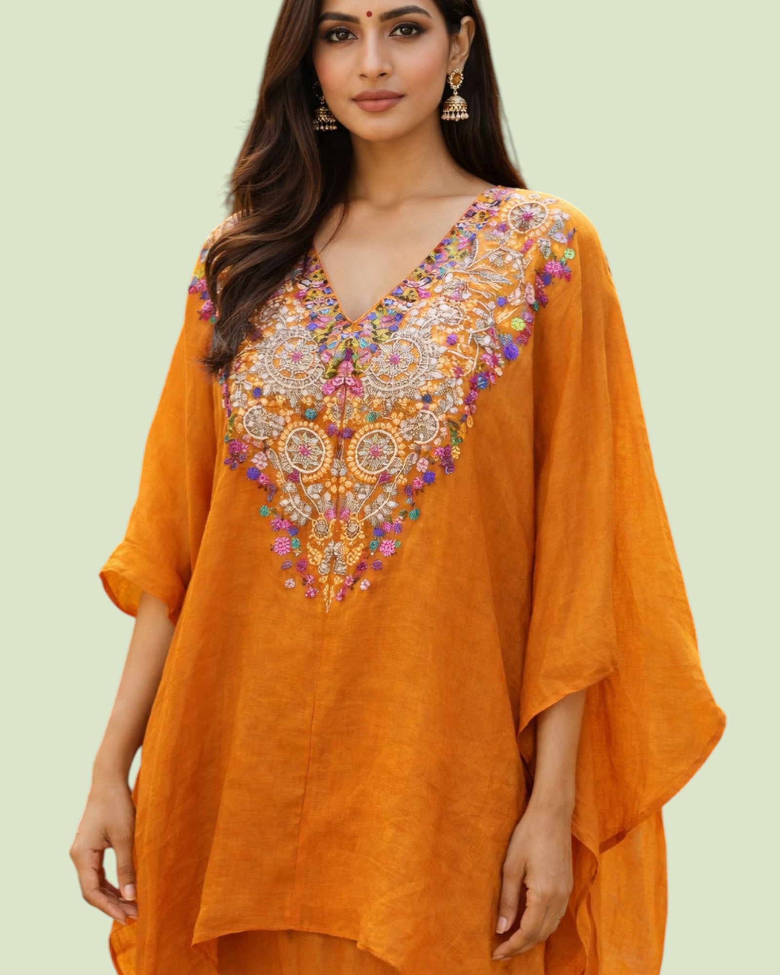 Woman wearing an orange embroidered dress on a light green background