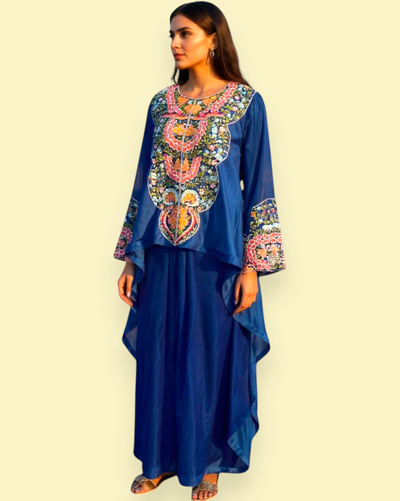 Woman wearing a blue dress with colorful embroidery on a beige background