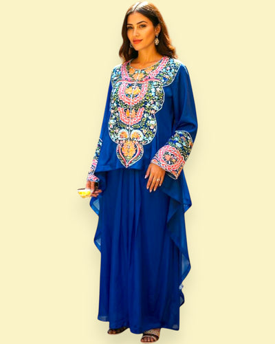 Woman wearing a blue dress with colorful embroidery on a beige background