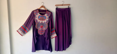 Purple embroidered top and skirt set on hangers against a white wall