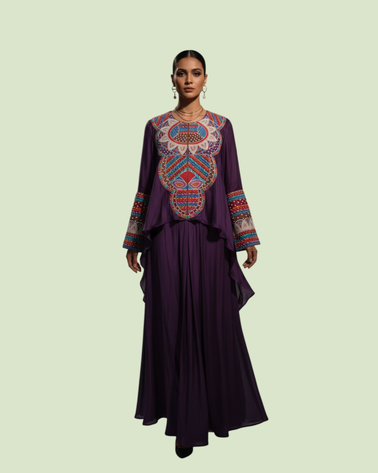 Woman wearing a purple dress with colorful embroidery on a light green background