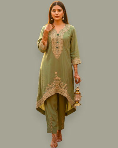 Woman wearing a green embroidered outfit holding a lantern on a gray background