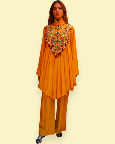 Woman wearing a mustard yellow outfit with intricate embroidery on a beige background