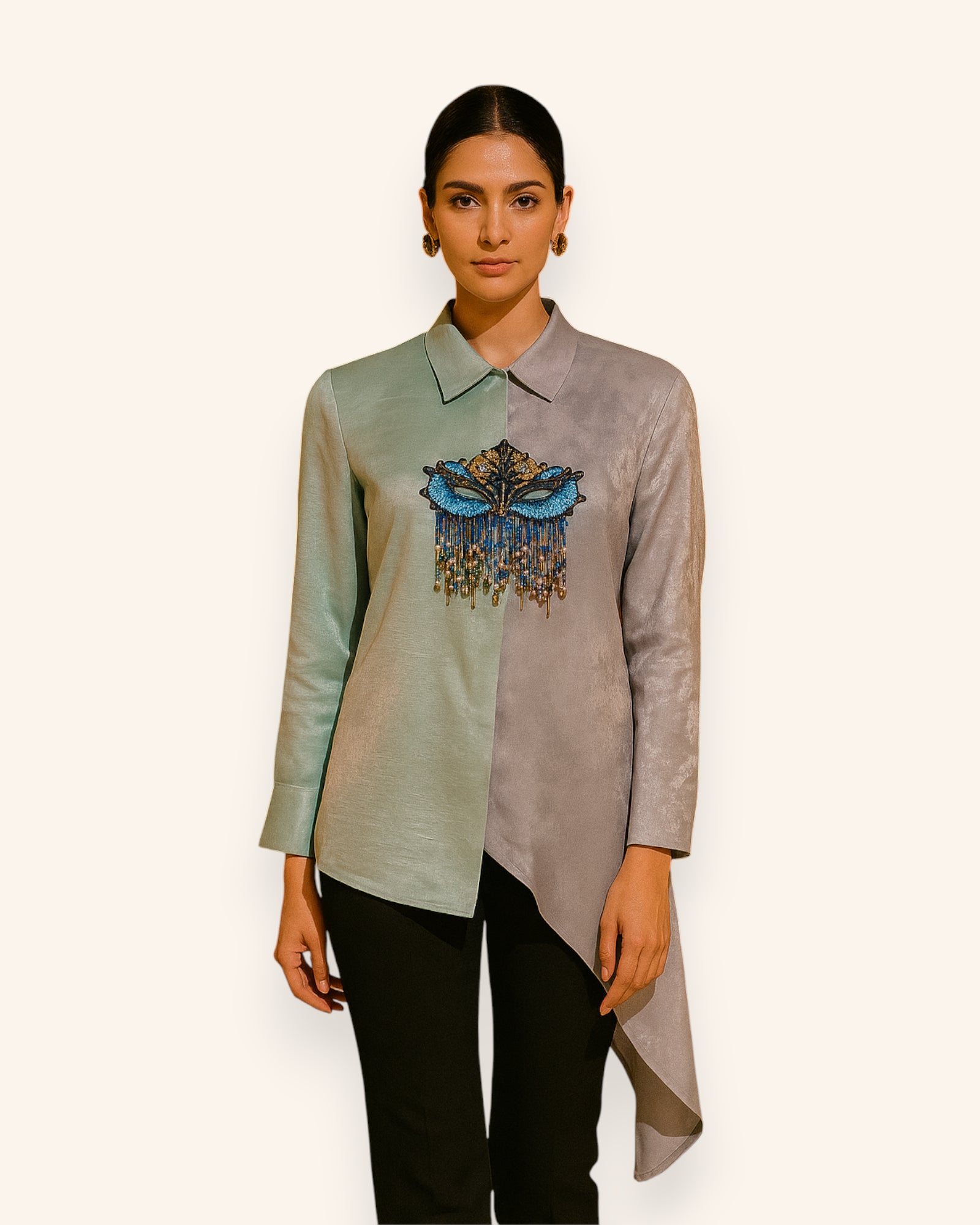 Woman wearing a long, light-colored shirt with a Mask design on a plain background