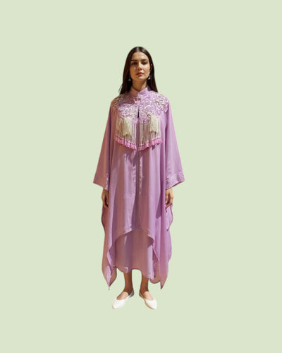Woman wearing a light purple dress with floral embroidery on a light green background