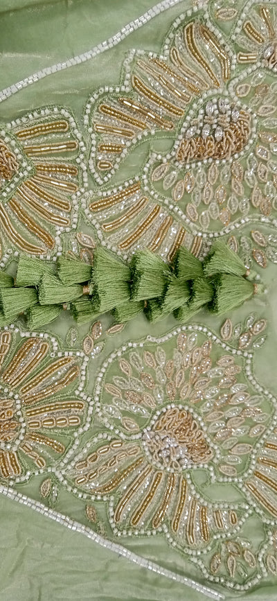 Close-up of green fabric with intricate gold and silver embroidery