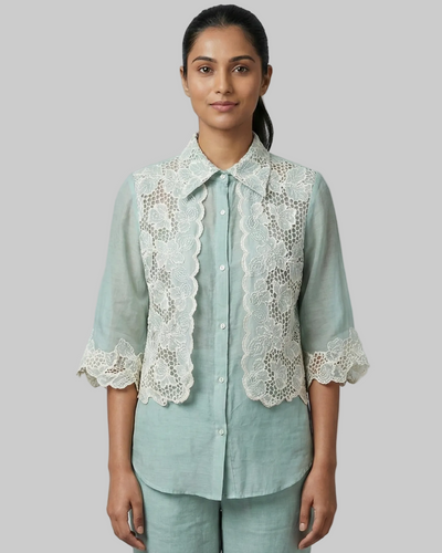 Woman wearing a light blue shirt with lace details on a gray background