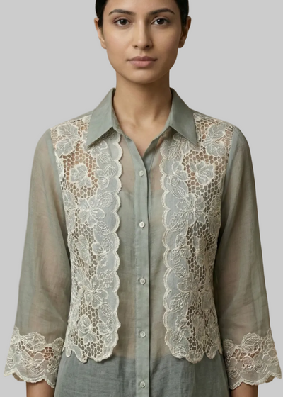 Woman wearing a light Blue shirt with lace detailing on a plain background