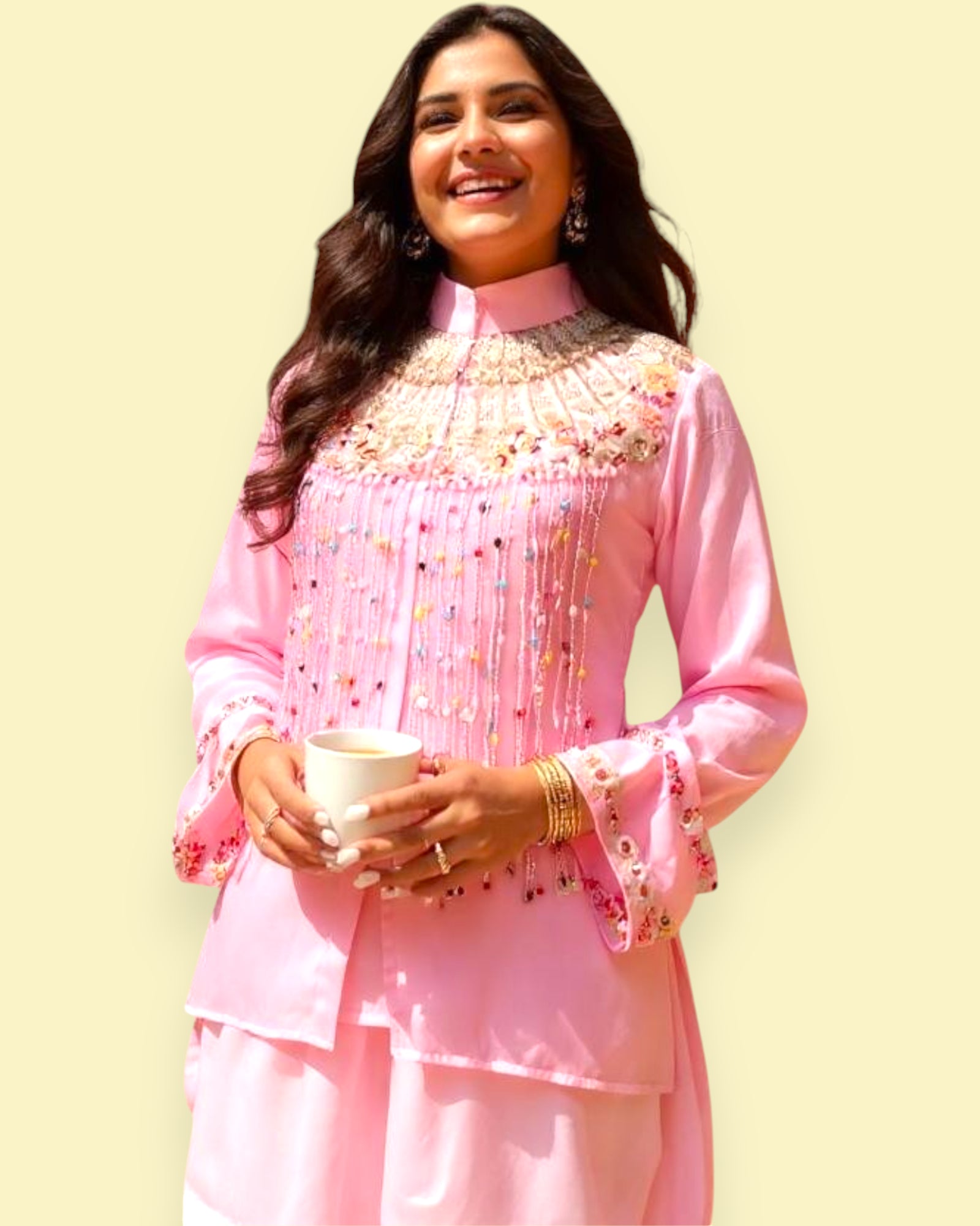 Woman wearing a pink traditional outfit with intricate designs on a light yellow background