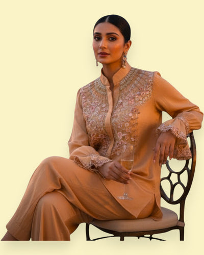 Woman in a traditional outfit sitting on a chair against a beige background