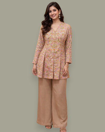 Woman wearing a floral top and brown pants on a gray background