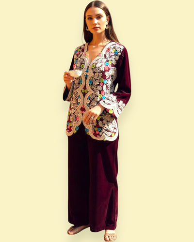 Woman wearing a traditional embroidered outfit with a plain background