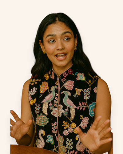 Woman wearing a black embroidered vest with colorful designs on a white background
