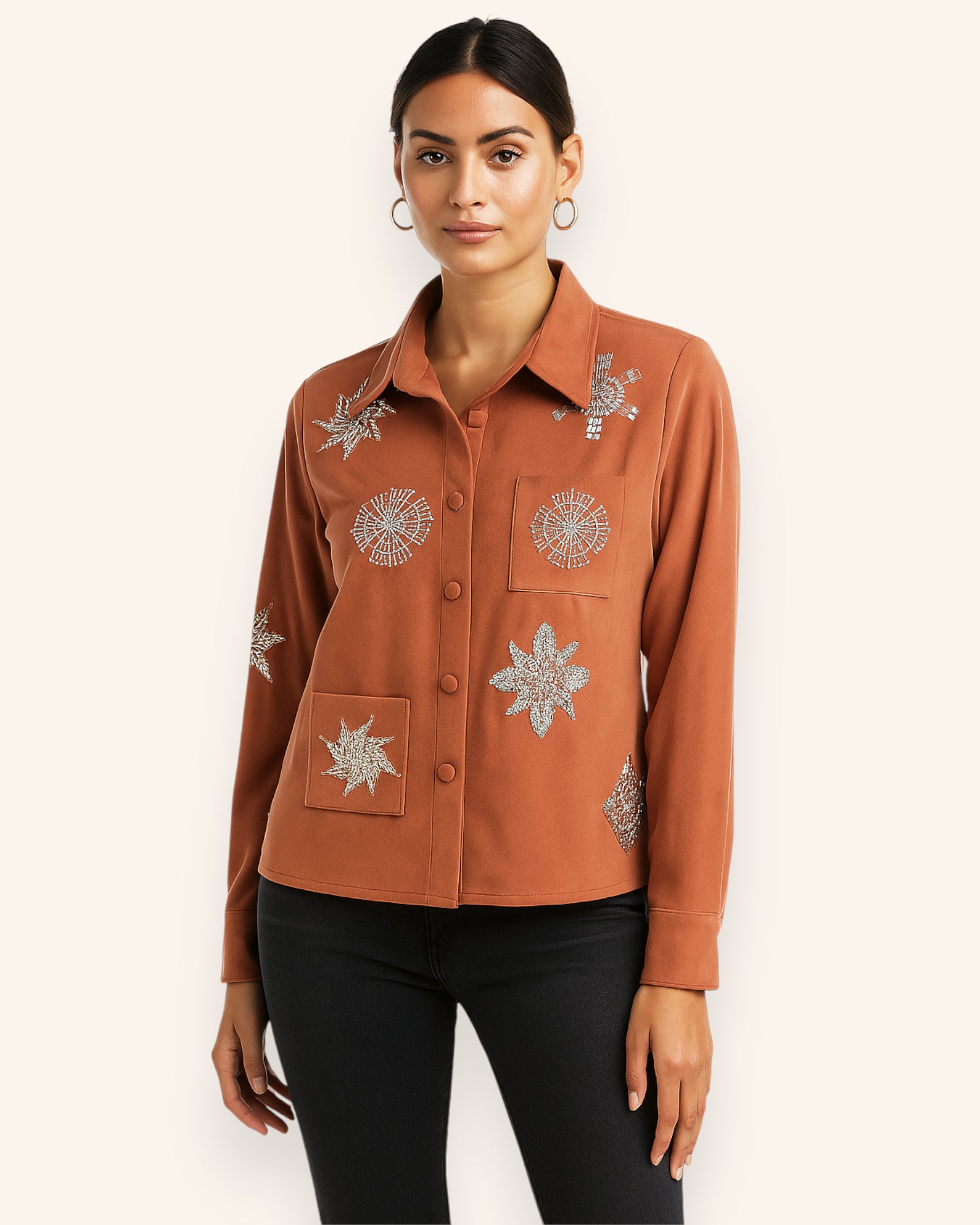 Woman wearing a brown jacket with silver floral embroidery on a white background