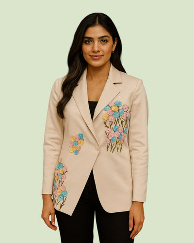 Woman wearing a beige blazer with floral embroidery on a light green background