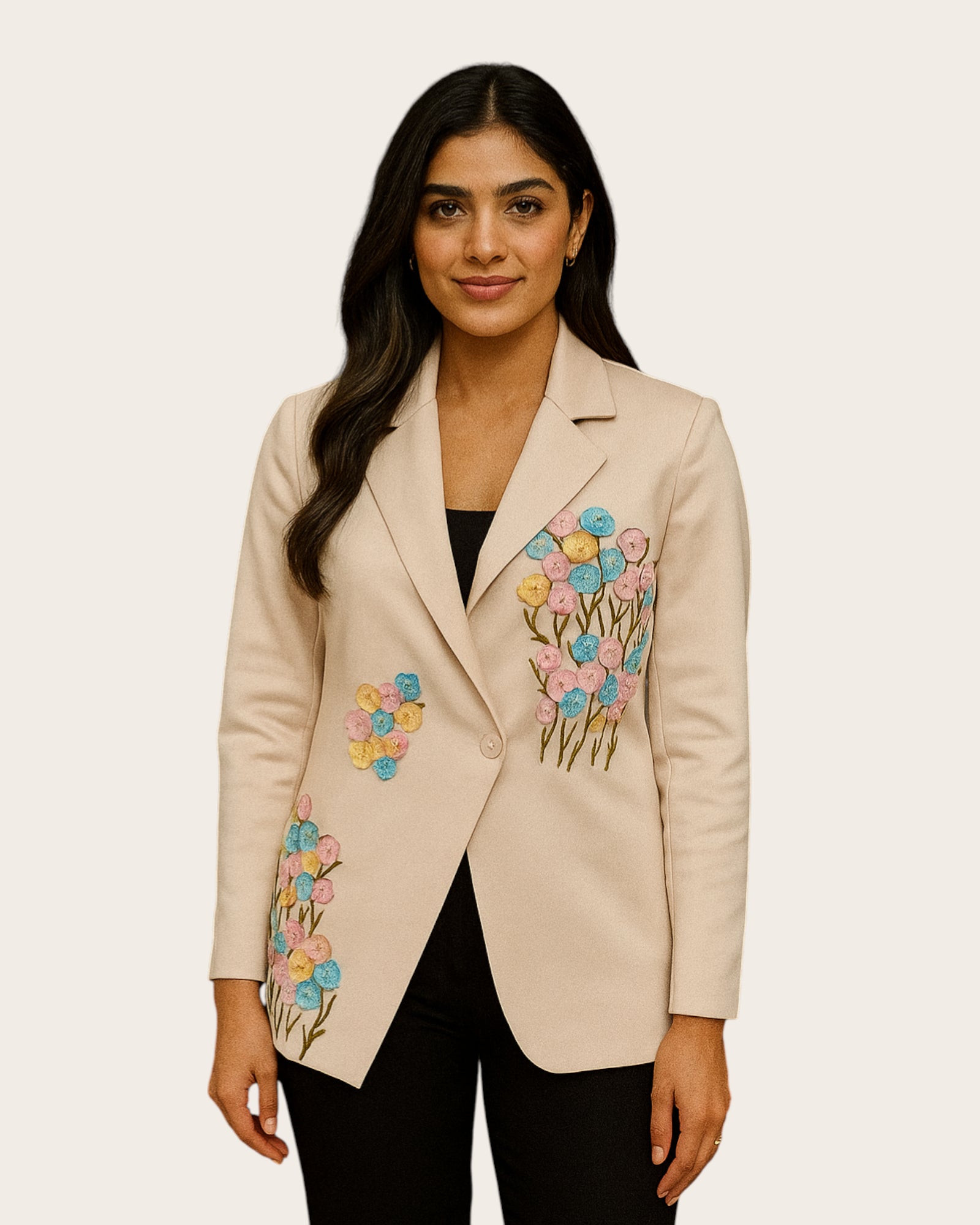 Woman wearing a beige blazer with floral embroidery on a plain background