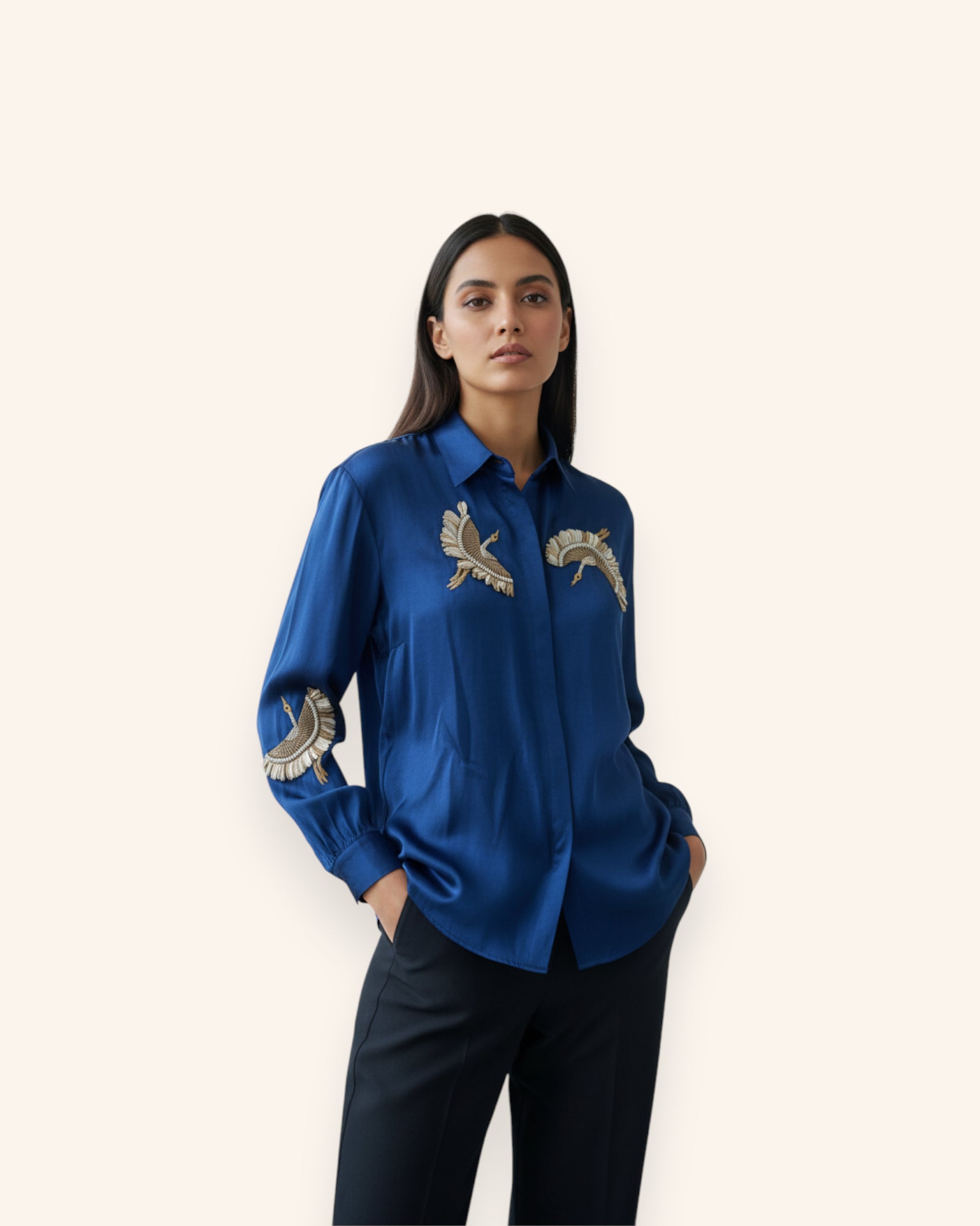 Woman wearing a blue shirt with embroidered designs on a white background