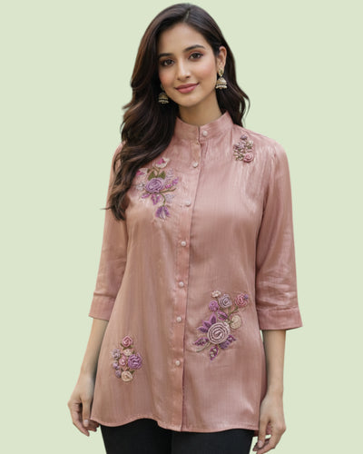 Woman wearing a pink embroidered blouse on a light green background