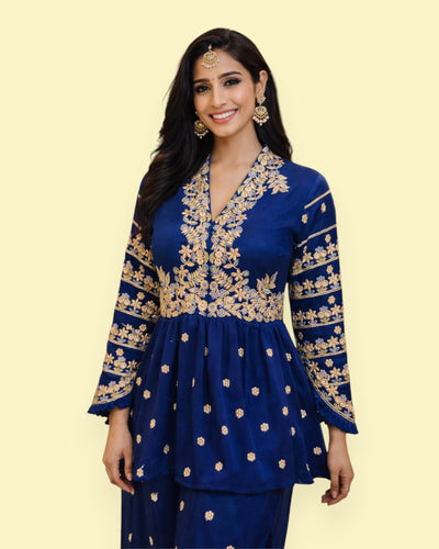 Woman wearing a blue embroidered outfit on a light green background