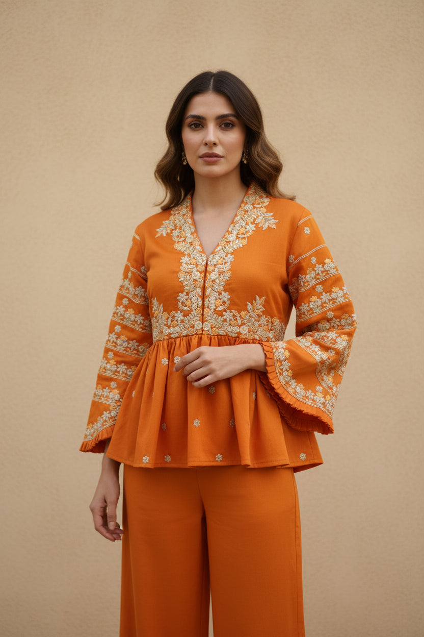 Woman wearing an orange outfit with intricate embroidery on a beige background
