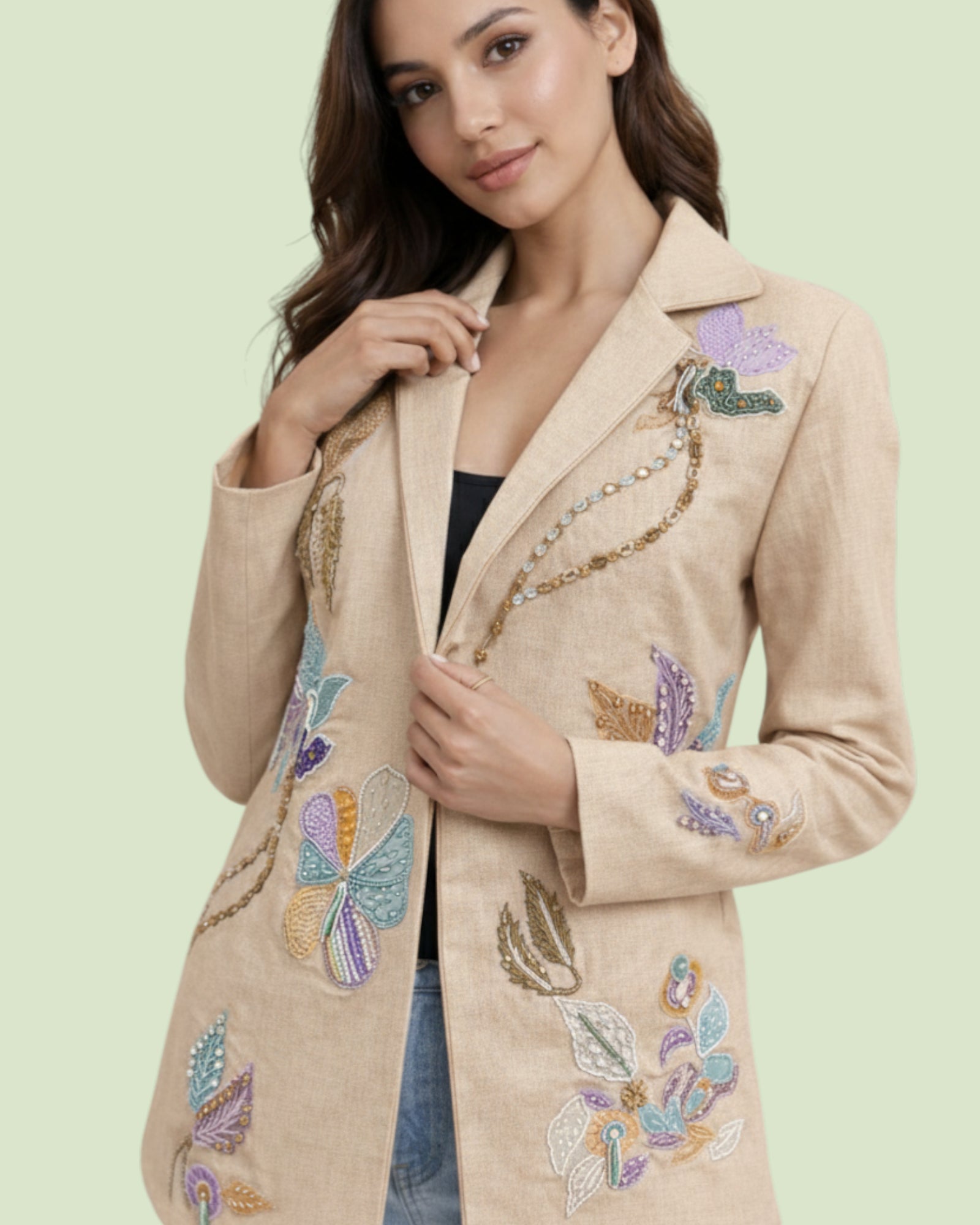 Woman wearing a beige blazer with colorful Flowers embellishments on a light green background