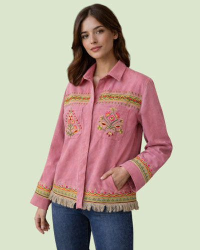 Woman wearing a pink embroidered shirt on a light green background