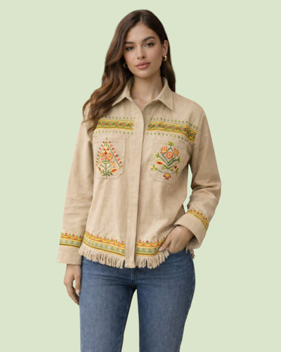 Woman wearing a beige embroidered jacket with floral patterns on a light green background